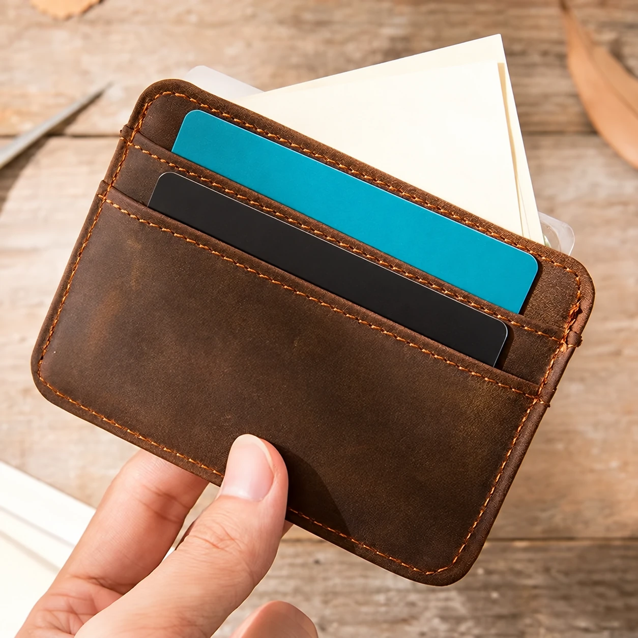 Brown stitched leather card holder with teal and black cards